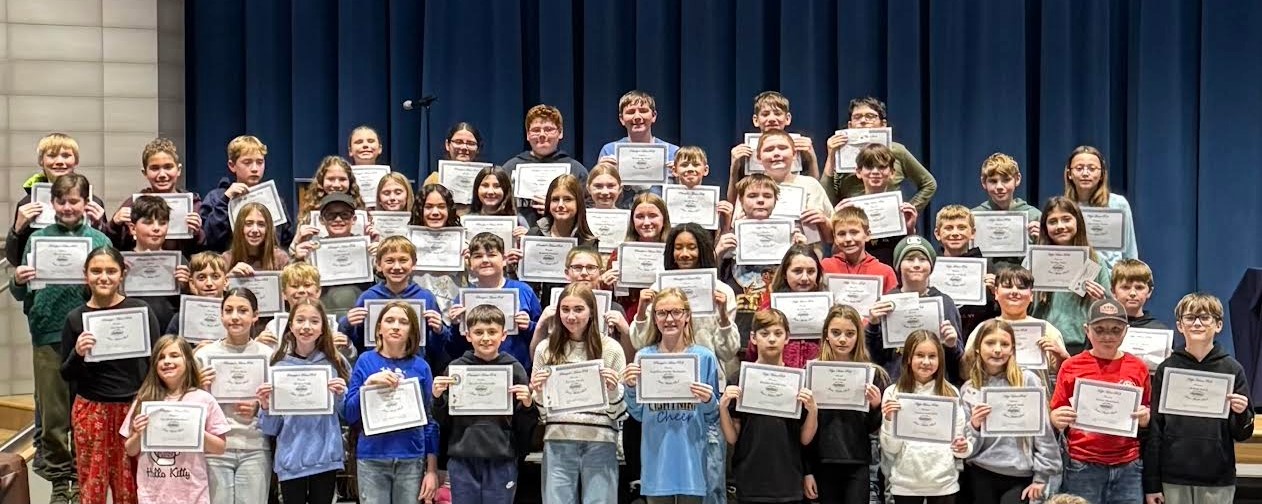 A large group of students hold up certificates, smiling for the camera.