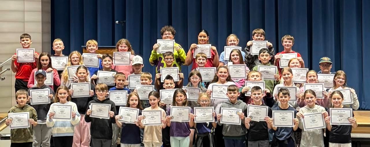 A group of students proudly hold up certificates, smiling for the camera.