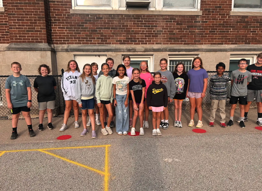 A group of diverse students stand together in front of a brick building.
