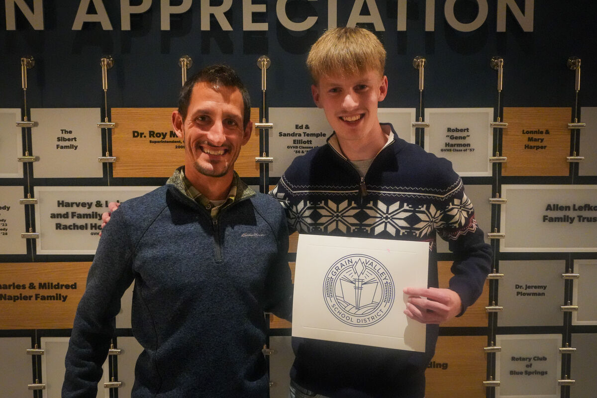 A photo of the cross country coach and Landon Blew holding an award. 