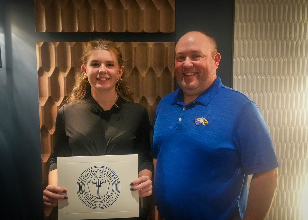 A photo of the golf coach and Amelia holding an award. 