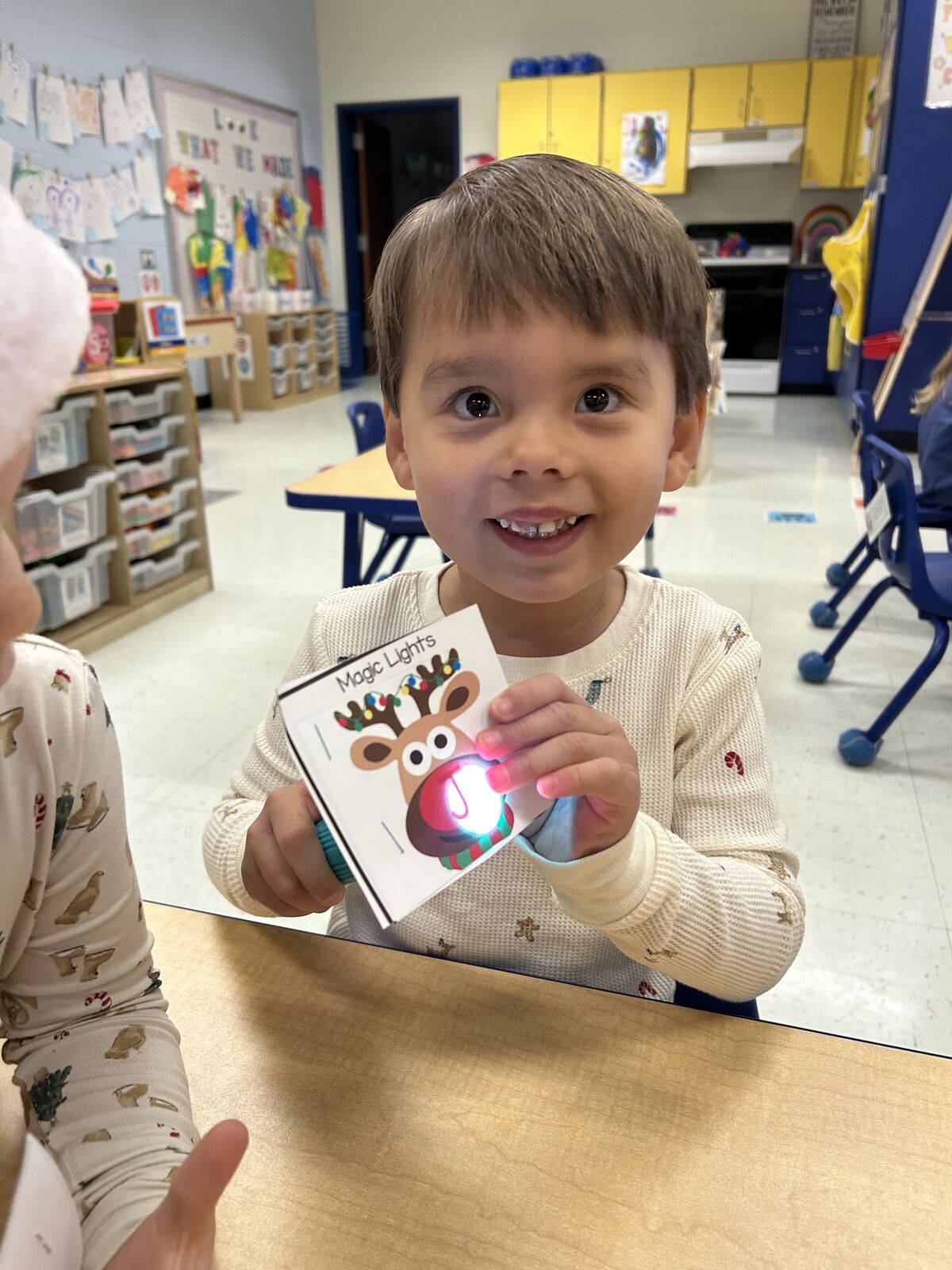 A young child smiles while holding a card with a glowing light.