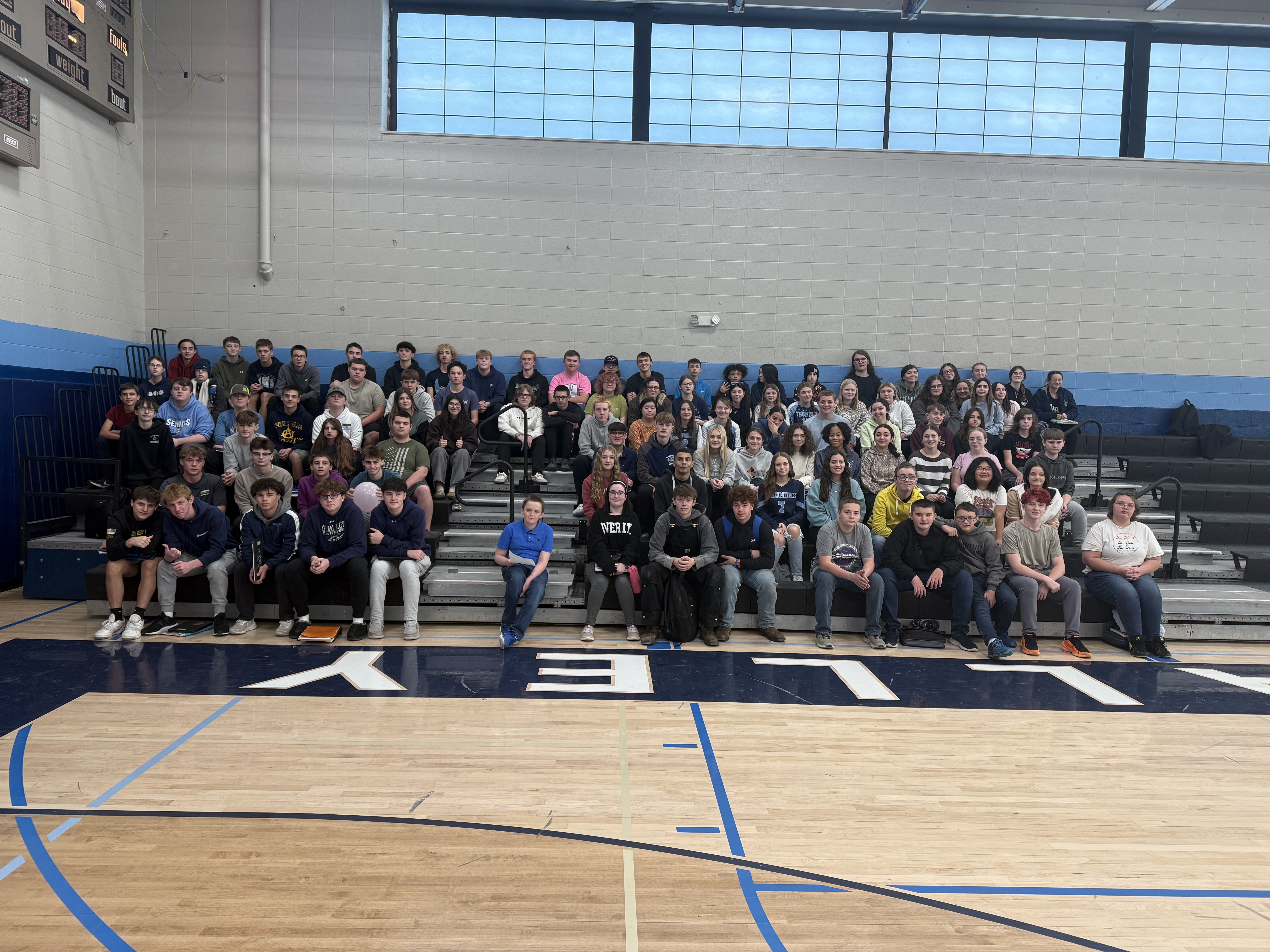 A large group of students poses for a photo in a gymnasium.