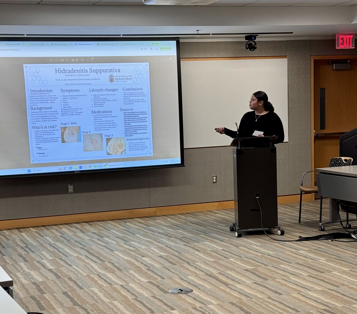 A woman presents information on a screen in a conference room.
