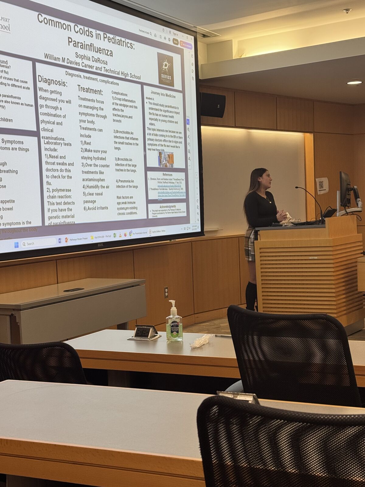 A person stands near a screen displaying a presentation about pediatric parainfluenza.