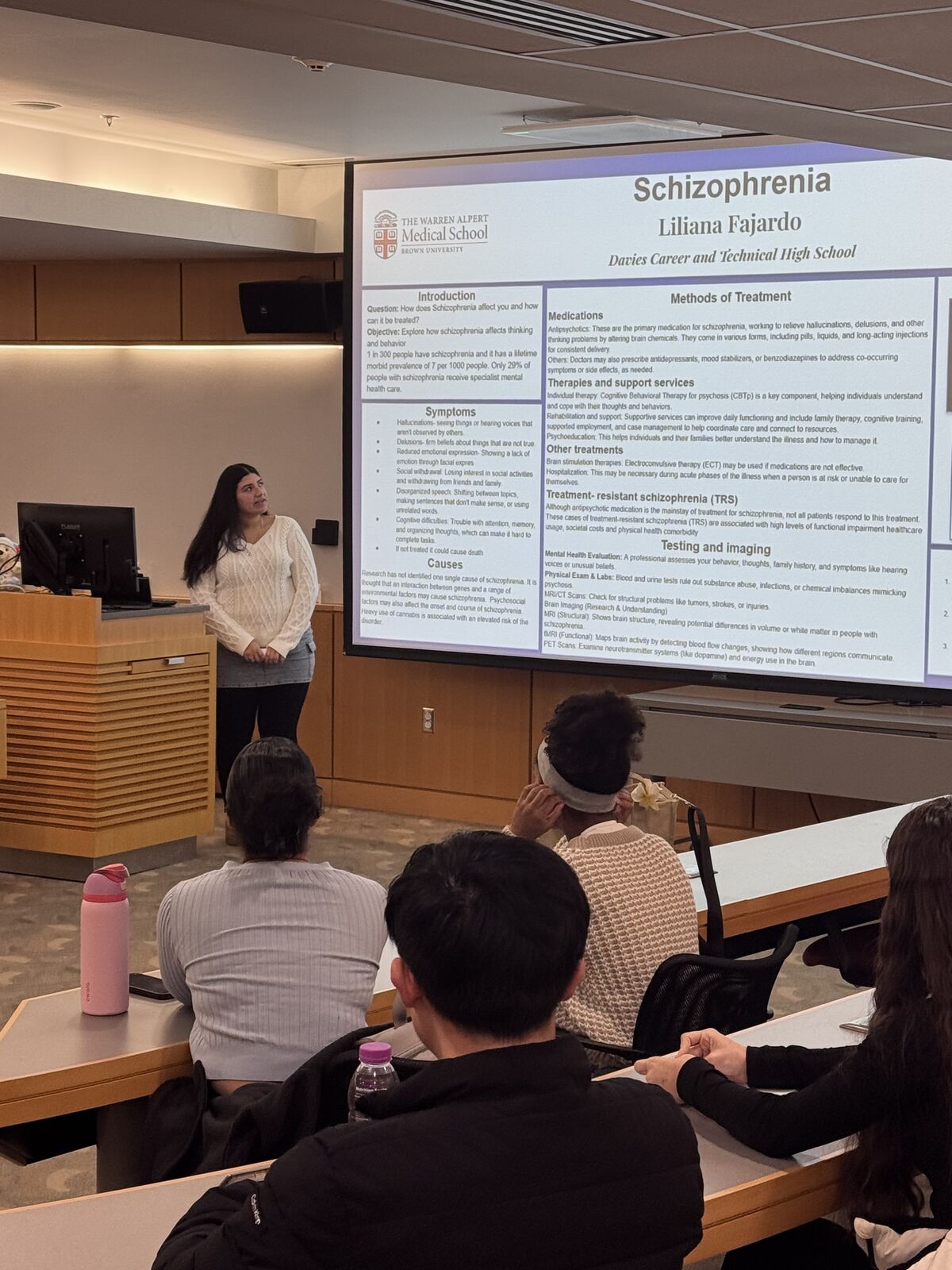 A presenter stands before a screen, giving a lecture on schizophrenia.