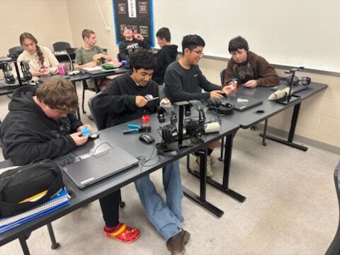 Students work on projects at desks in a classroom setting.