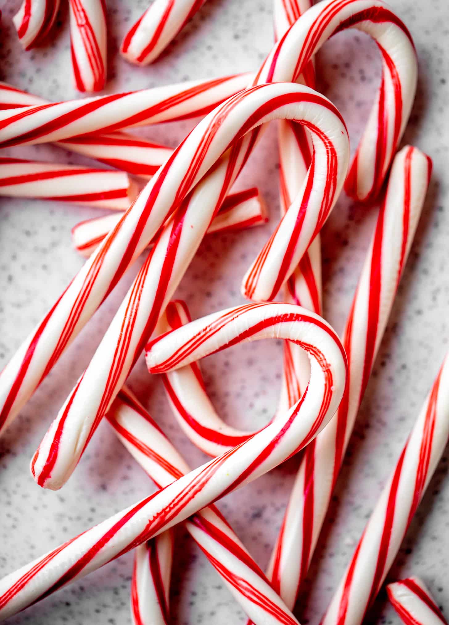 A close-up overhead view of a pile of red and white striped candy canes.