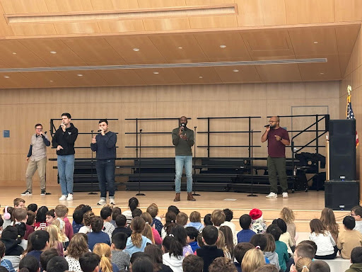 Performers on stage singing during assembly.