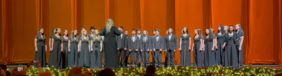 A choir of young people in formal black attire performs on a stage at Radio City.