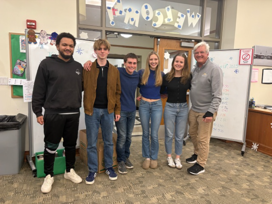 Cross Country teammates and coaches pose for photo in High School library.