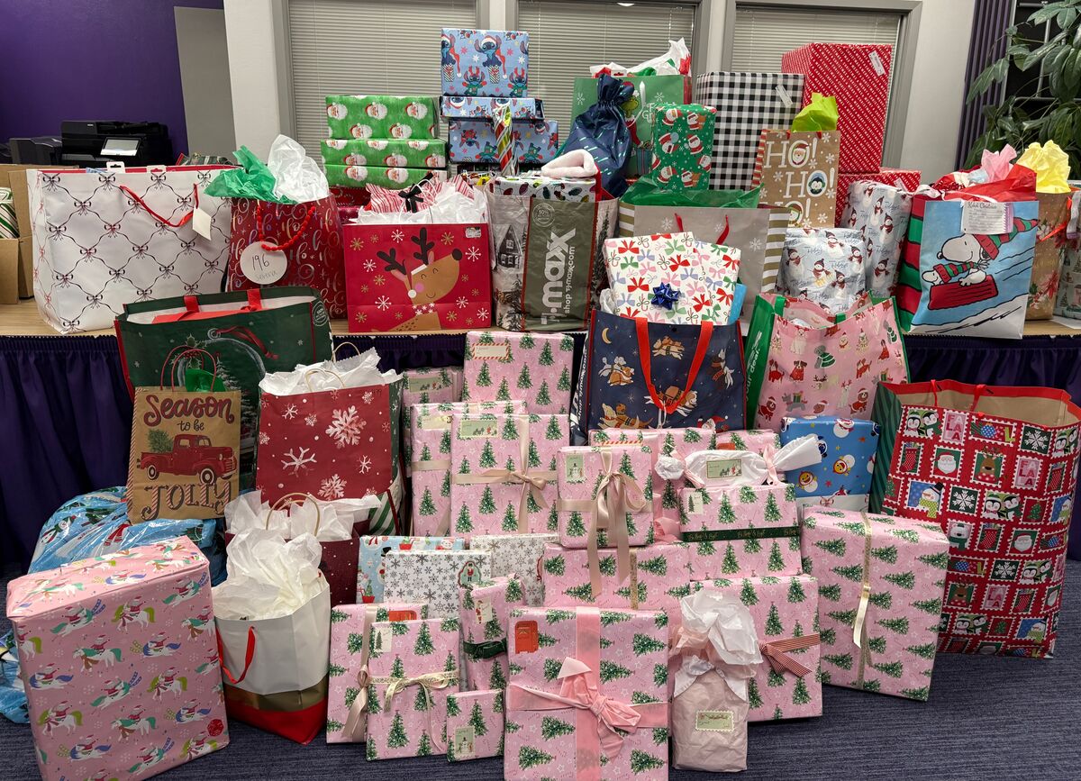 A large collection of Christmas gifts wrapped in festive paper and placed in gift bags.