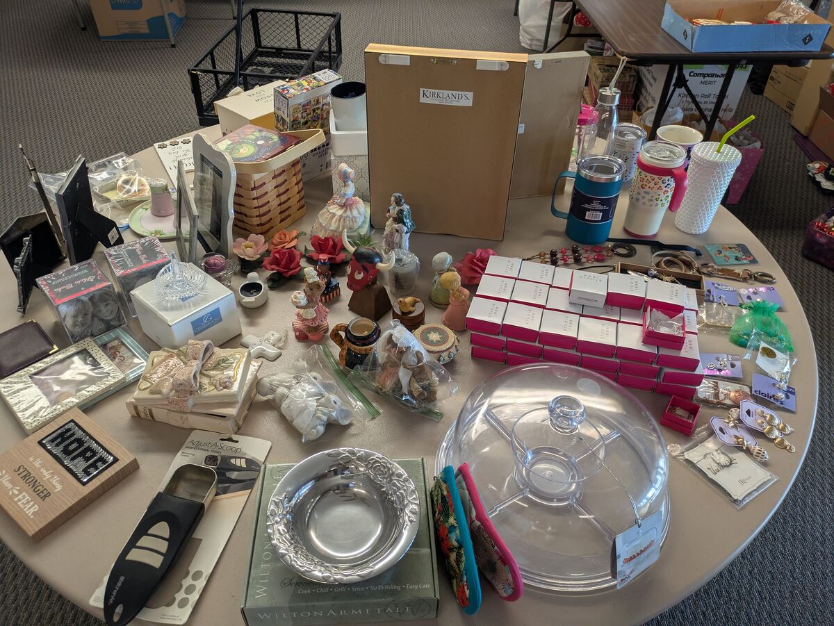 A collection of decorative items, including photo frames, figurines, jewelry, and kitchenware, are displayed on a table.