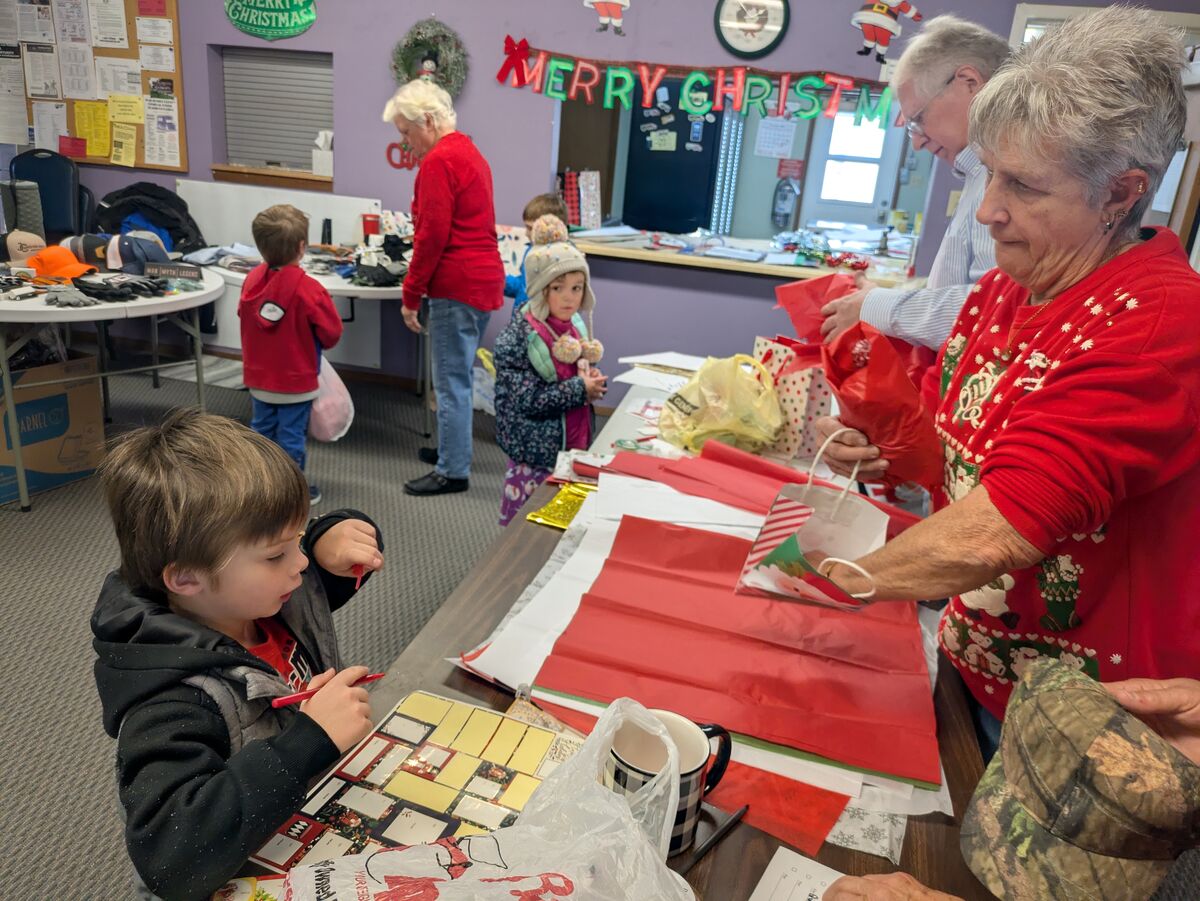 People are gathered around a table, preparing gifts and decorations for Christmas.