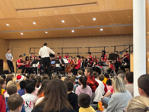 Students on stage playing musical instruments during winter concert. 