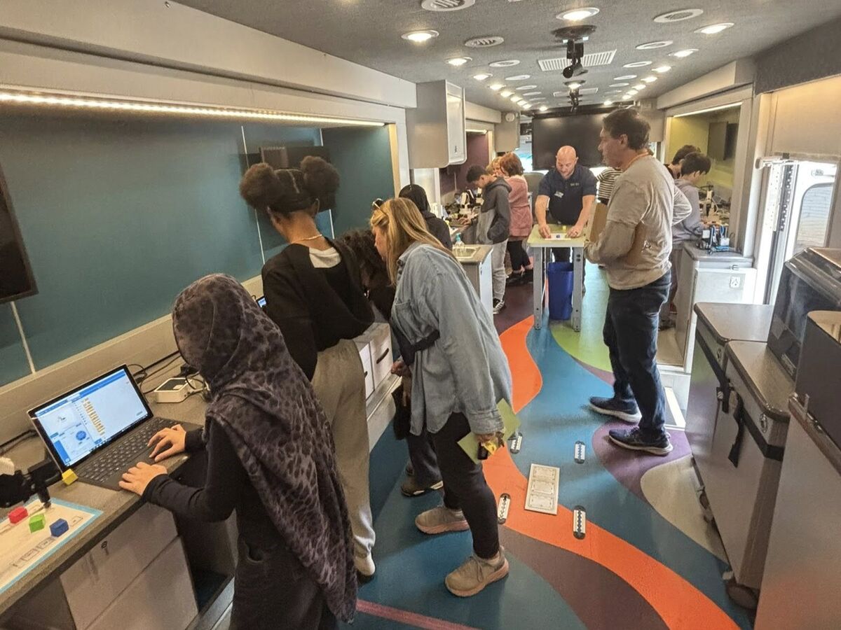 A group of students and an adult engage with interactive displays inside a mobile learning lab.