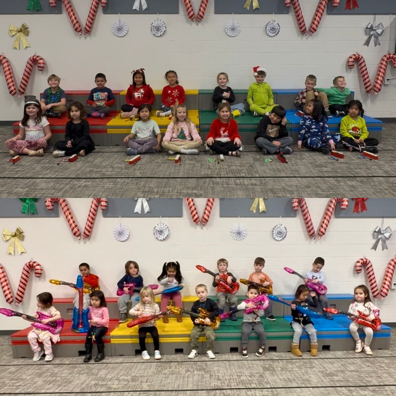 Children in festive attire sit on colorful risers, some holding toy guitars, with candy cane decorations.