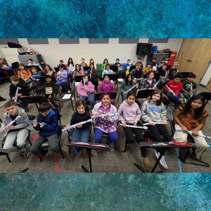 A diverse group of students sits in chairs holding recorders, ready for music class.