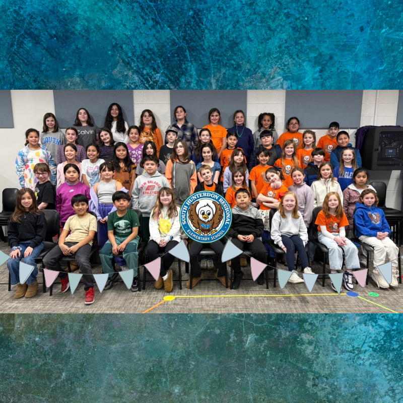 A large group of elementary school students pose for a photo, with many wearing orange shirts.