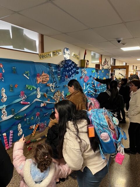 Students and their families observe a mural display of seahorses and fish in the hallways of LaMonte Annex that the students helped create for their unit focused on coral reef animals, habitats and ocean life