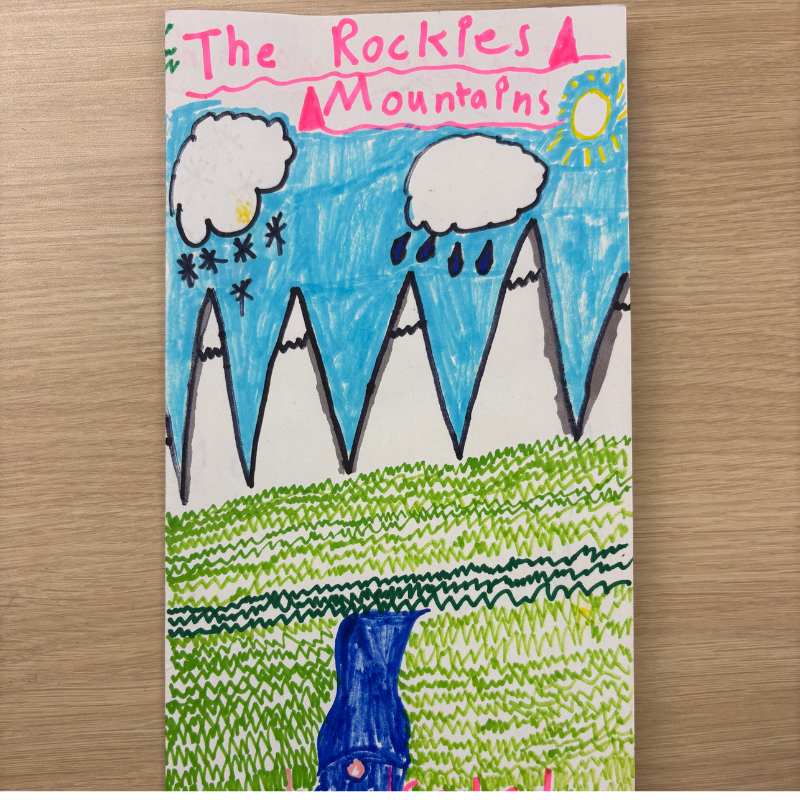 A colorful drawing depicts the Rocky Mountains with snow-capped peaks, a blue sky, clouds, and a bright sun.
