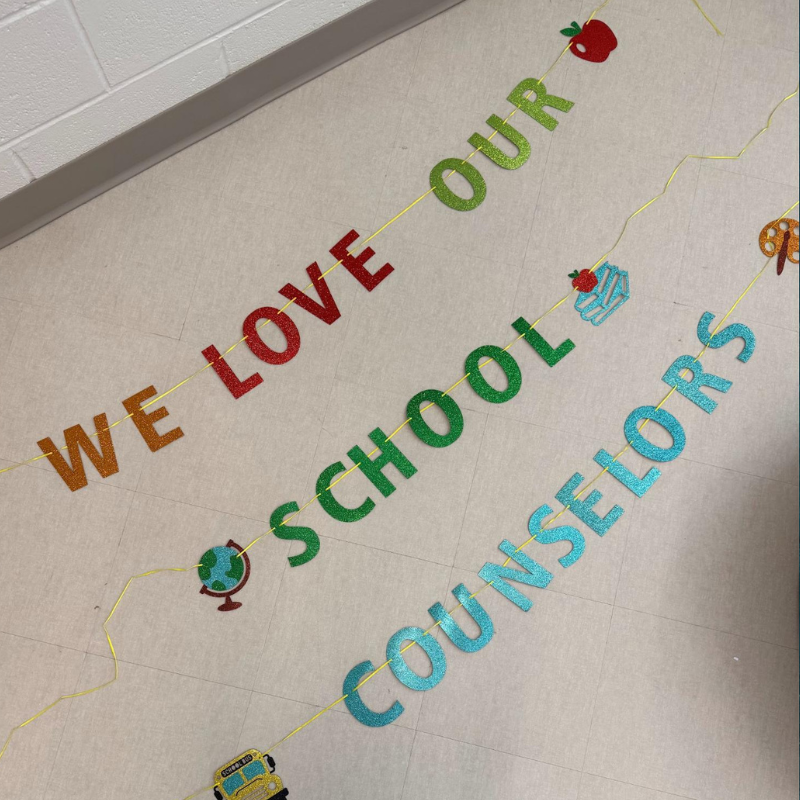 Glittery letters spell out 'WE LOVE OUR SCHOOL COUNSELORS' on a tiled floor.