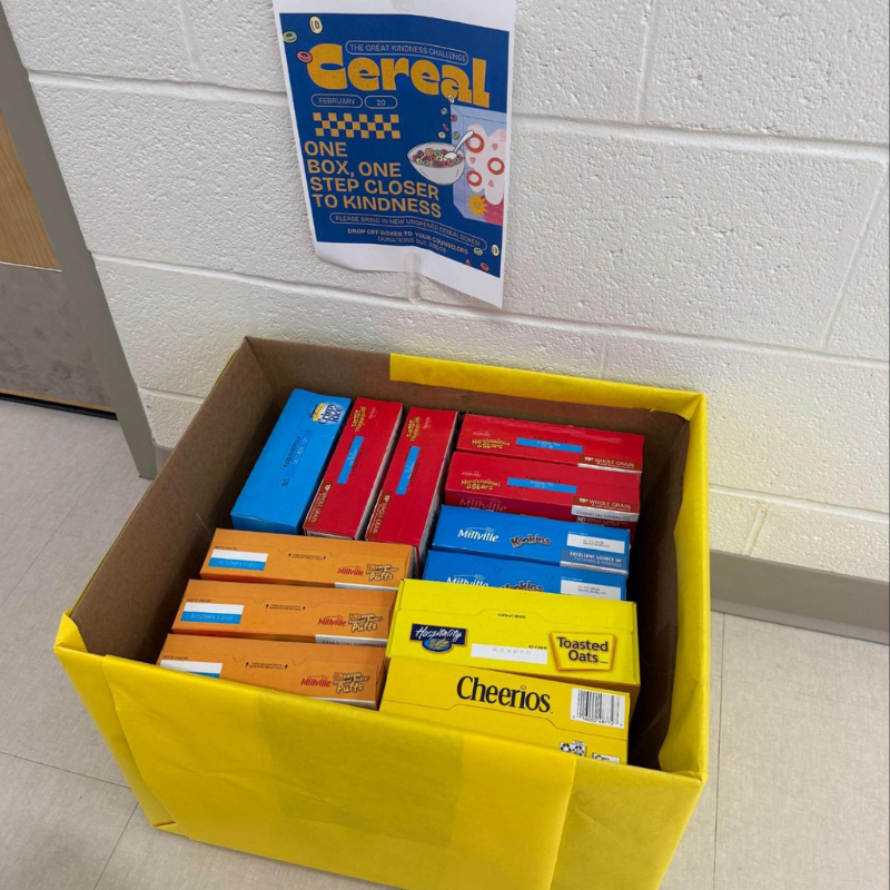 A bright yellow bin overflowing with assorted cereal boxes, including Cheerios and Millville.