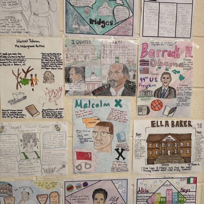 A wall display features student projects on historical figures like Harriet Tubman, Malcolm X, and Barack Obama.