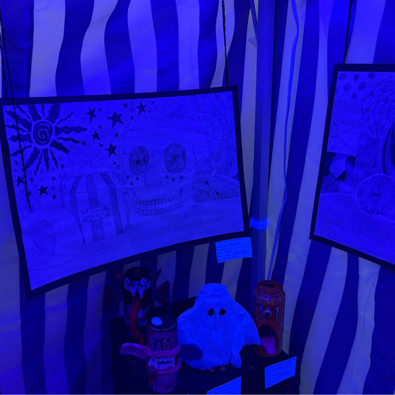 A display of Halloween-themed artwork and crafts under blue lighting.