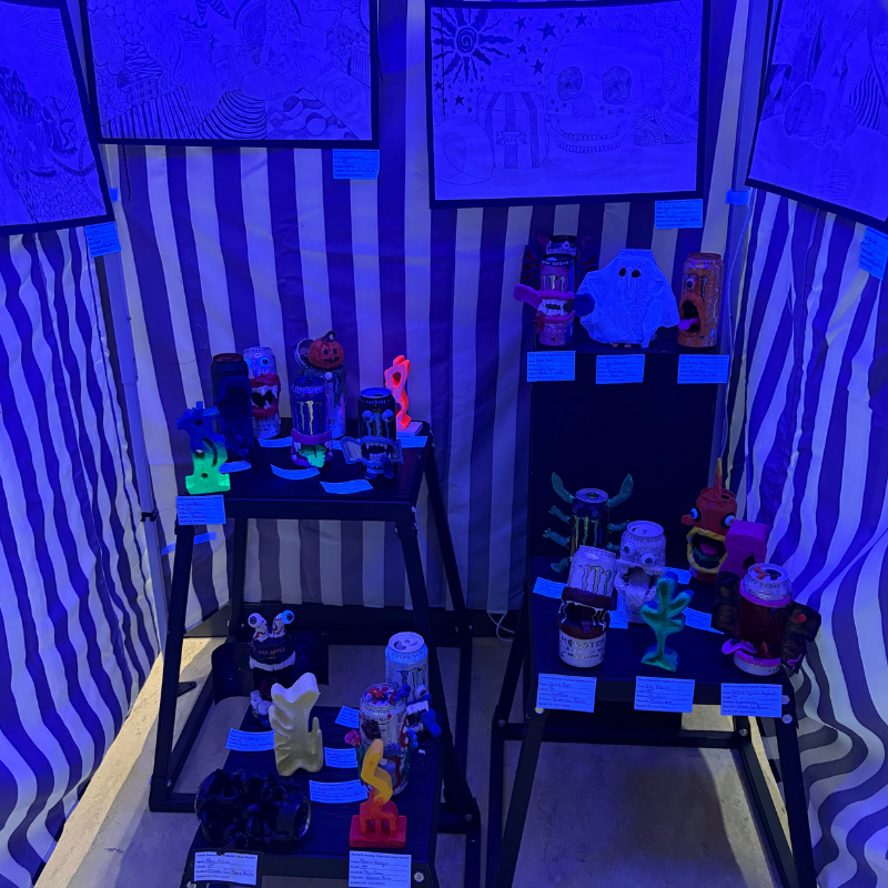 A display of colorful, sculpted figures and artwork illuminated by blue light.