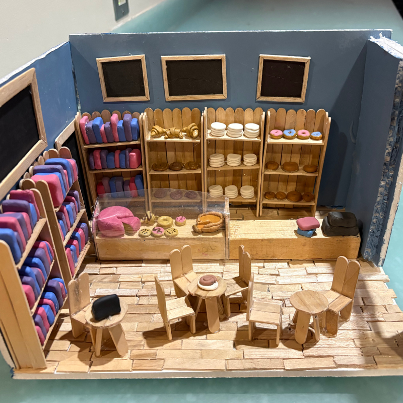A miniature bakery scene with shelves stocked with colorful pastries and baked goods.