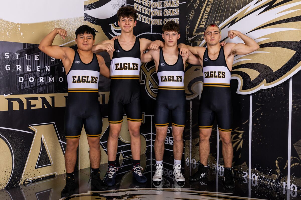 Four young men in wrestling singlets with 'EAGLES' on them pose for a photo.