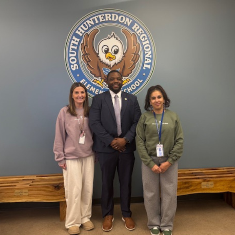Three people stand in front of the South Hunterdon Regional Elementary School logo.