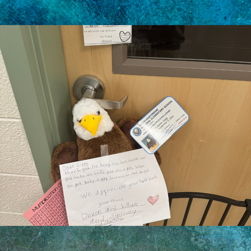 A stuffed eagle toy hangs on a door handle, adorned with notes and a multiplication chart.