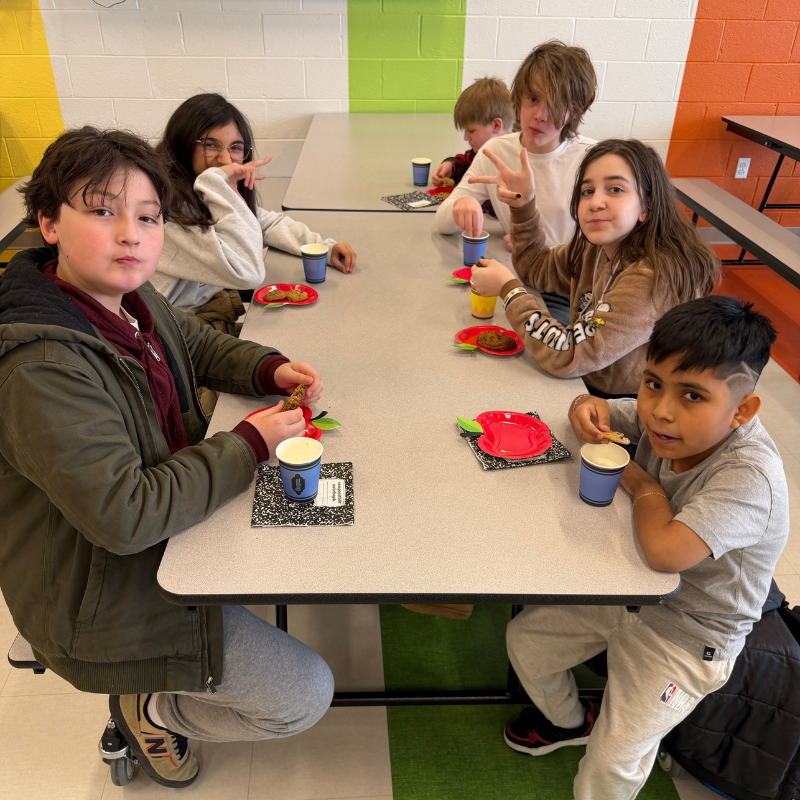 A group of children sit at a table, enjoying snacks and drinks.