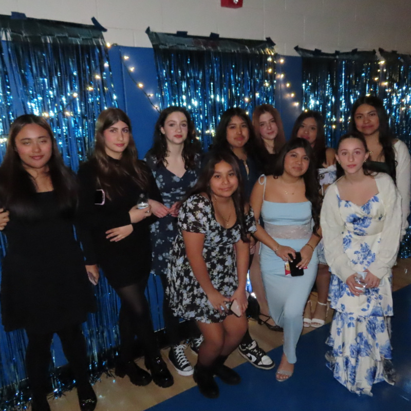 A group of young women pose for a photo in front of a blue sequined backdrop.