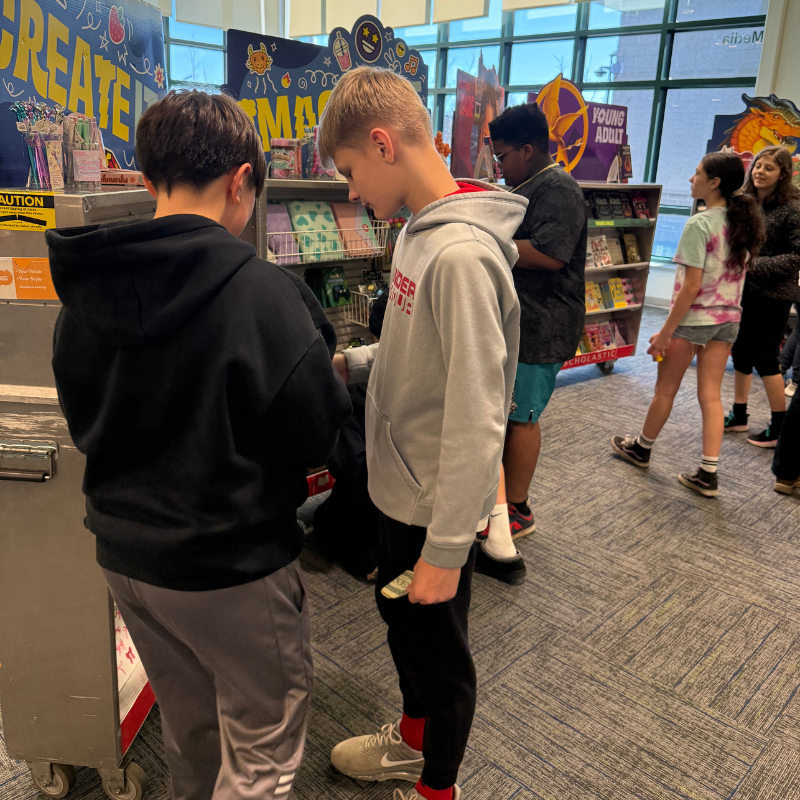 Two boys look at items displayed on a shelf in a store.