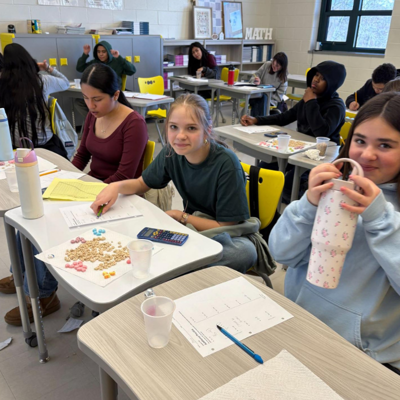 Students work at desks in a classroom, with a "MATH" sign visible on the wall.
