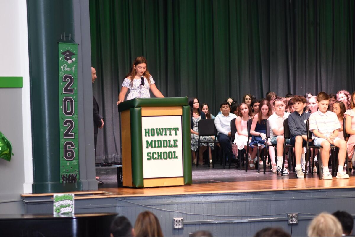 A young speaker addresses an audience from a podium at Howitt Middle School.