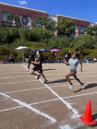 A group of RCMS track students at the finish line of a running track.