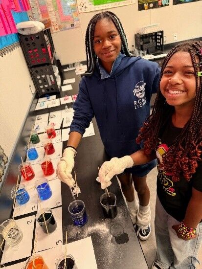 Two smiling students displaying their science project.