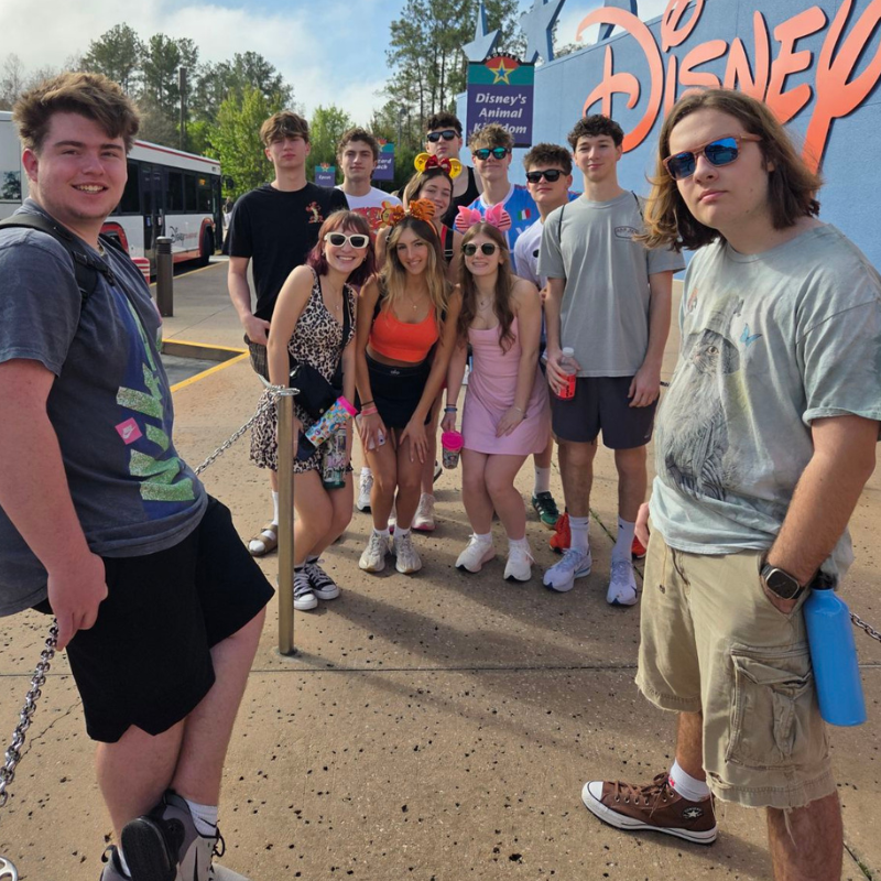 A group of young people pose for a photo in front of the Disney's Animal Kingdom entrance.