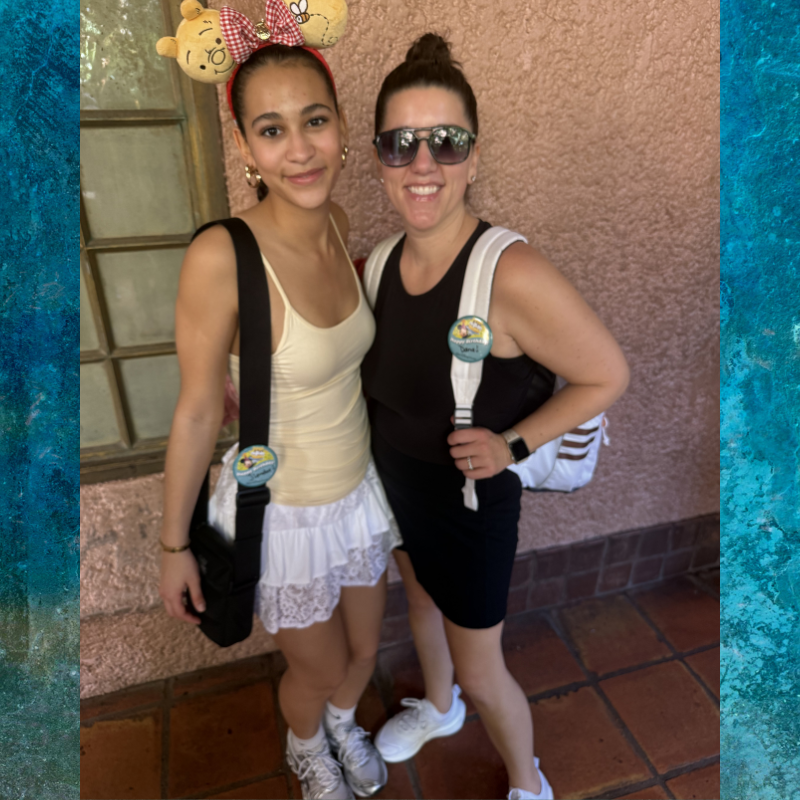 Two smiling women pose for a photo, one wearing Winnie the Pooh ears.