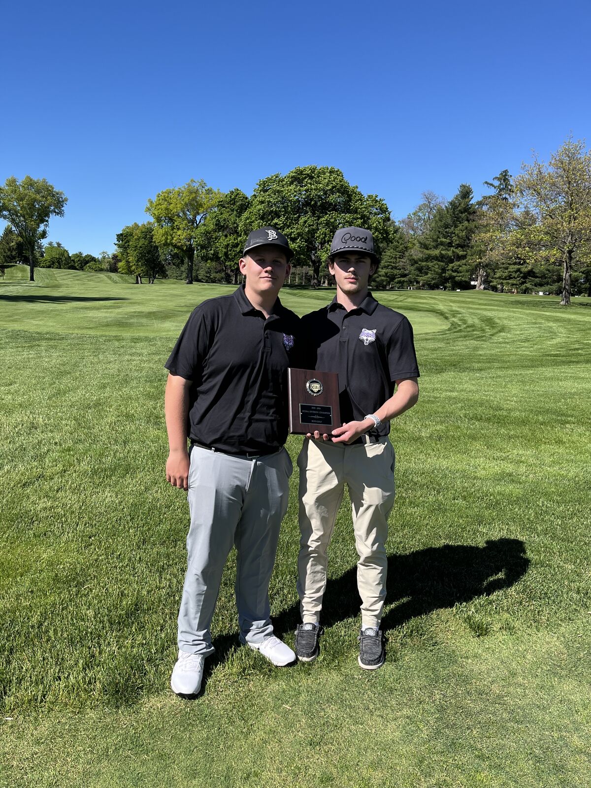 Two golfers pose with a plaque