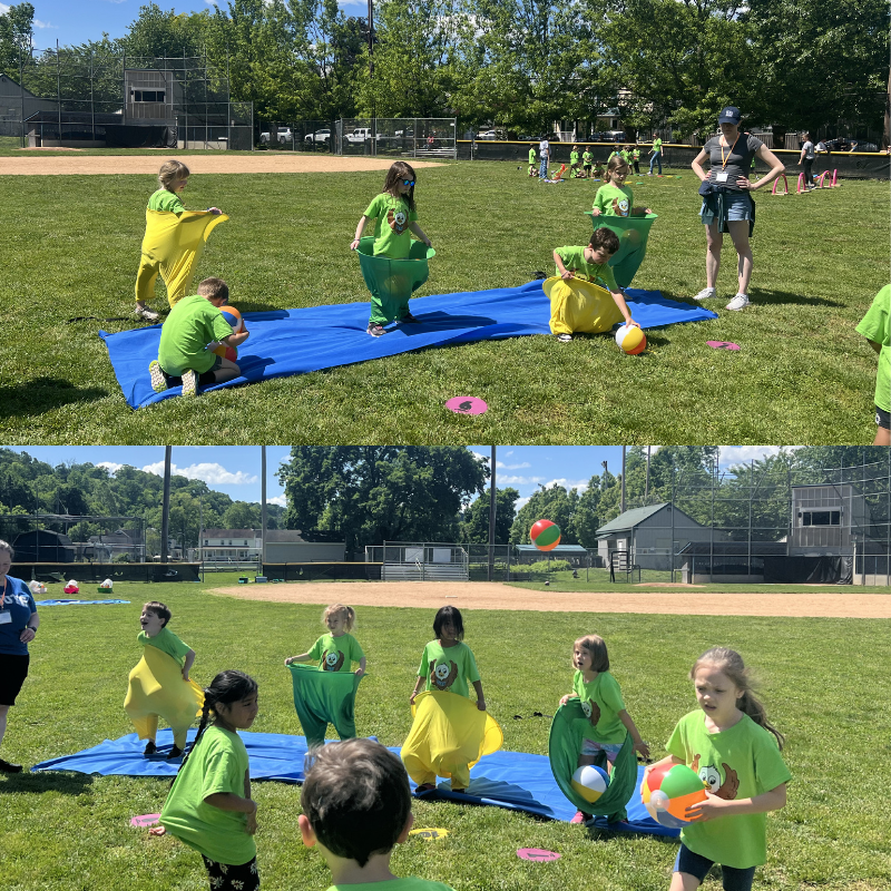 Children in green shirts participate in a sack race on a grassy field, some with colorful balls.