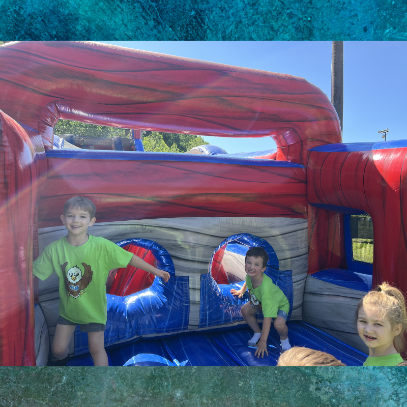 Children joyfully play inside a large, inflatable bounce house with red and blue accents.