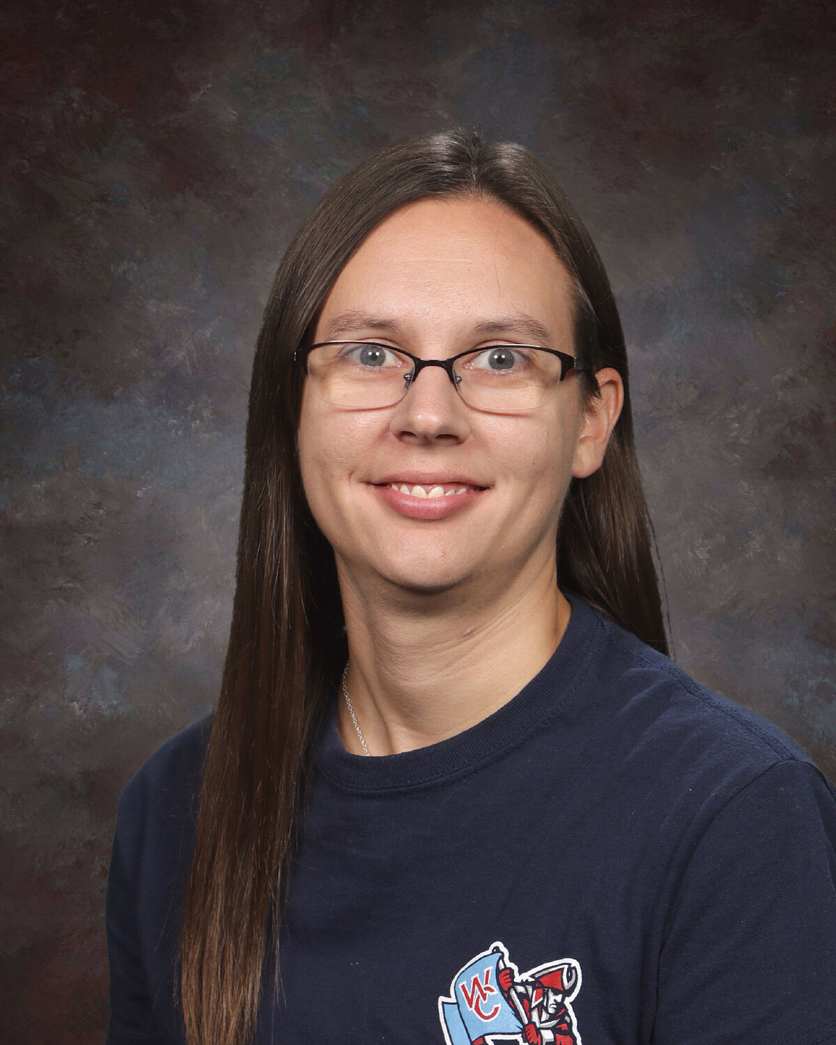 Ms. Kleynenberg A woman with long brown hair, glasses, and a dark blue shirt smiles in a studio portrait.