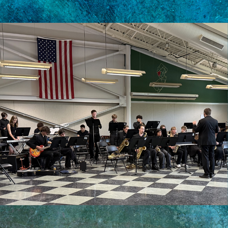 A high school jazz band performs with a conductor leading them.