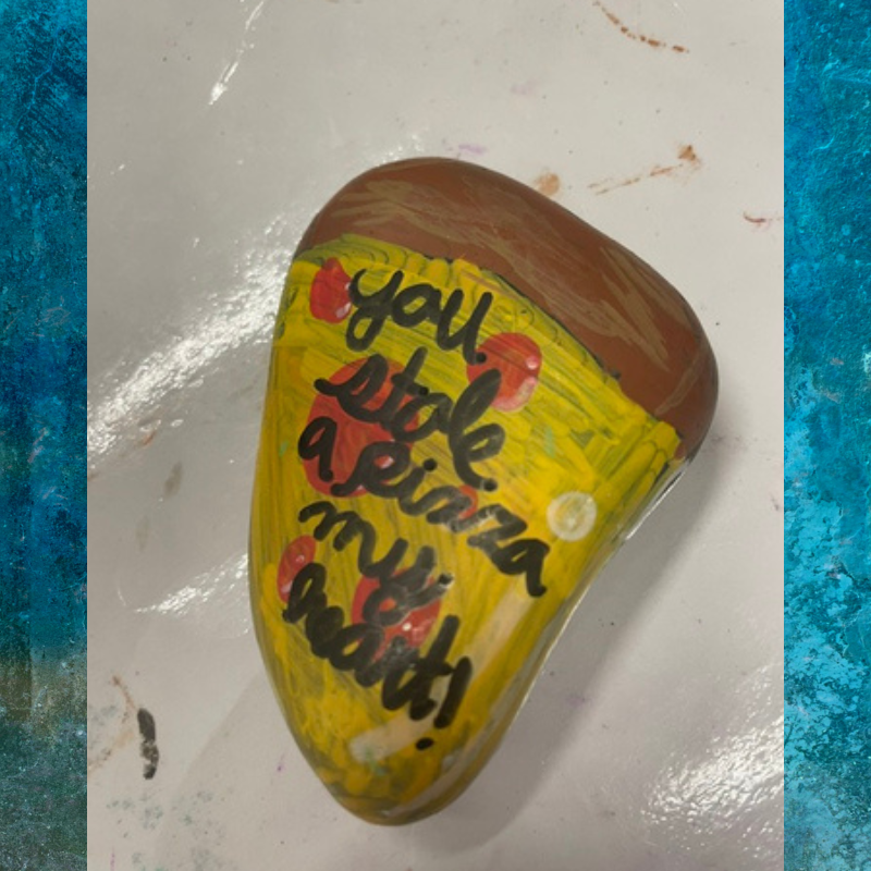 A painted rock shaped like a slice of pizza with the text 'You stole a pizza my heart!'
