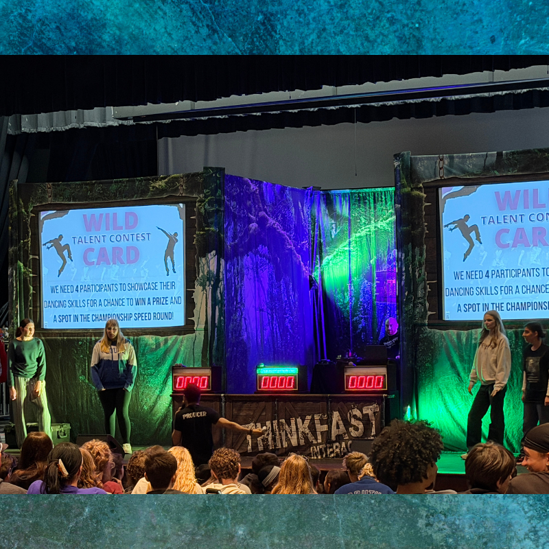 A stage set for a talent contest with screens displaying "WILD TALENT CONTEST CARD" and jungle-themed backdrops.